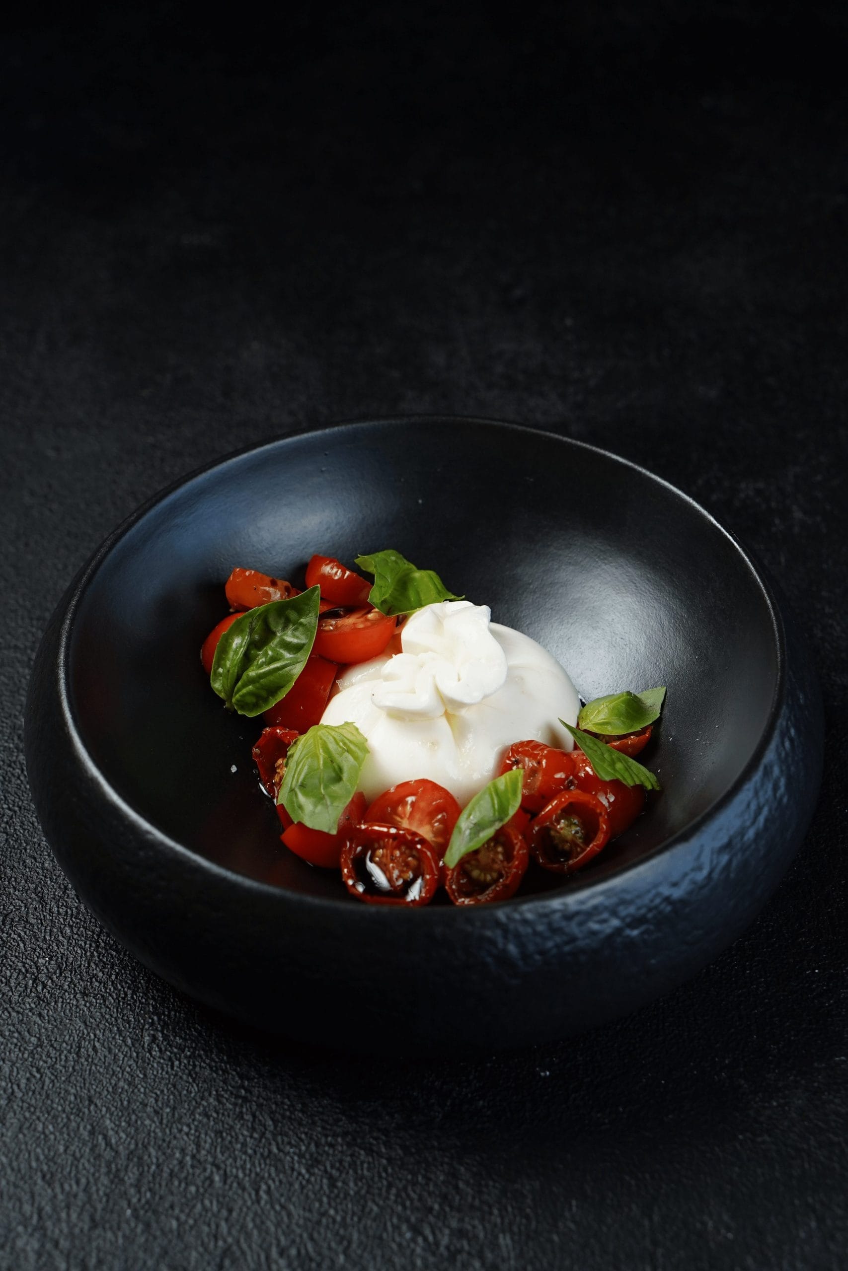 A gourmet dish of burrata with tomato and basil