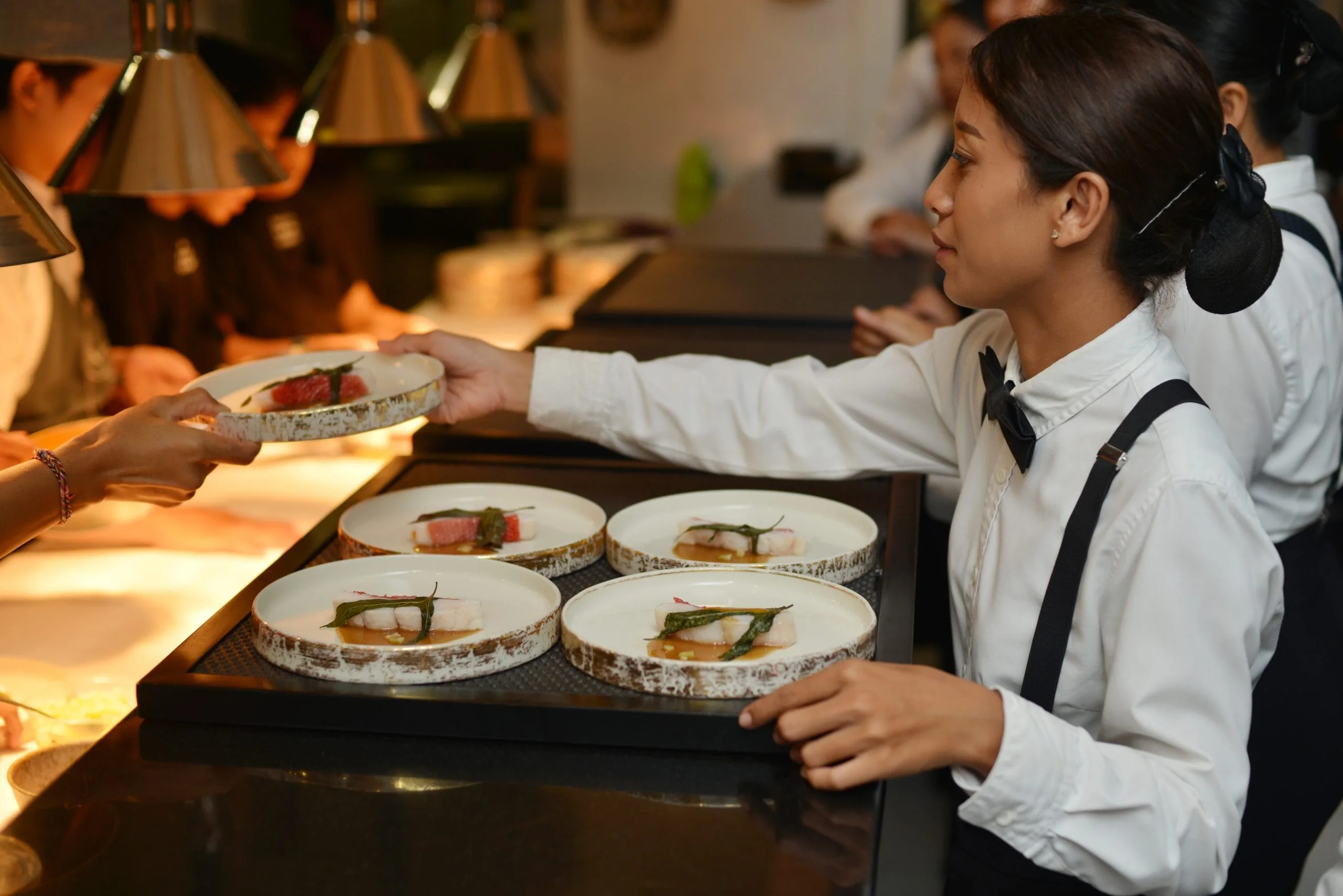 An event and party catering Bali staff member taking out plated meals for guests