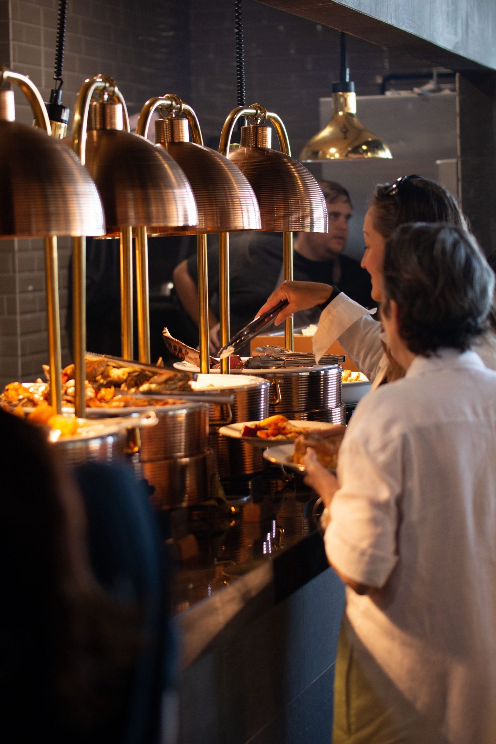 Two women serving themselves a meal from a buffet in Bali