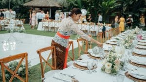 A traditionally dressed Balinese woman served a table at a wedding