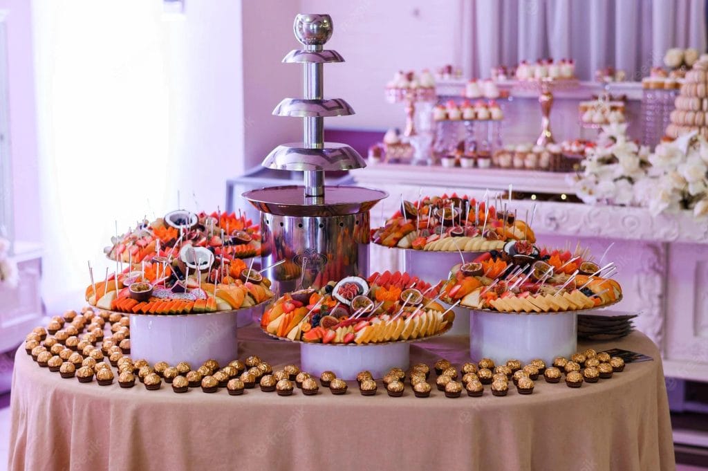 A chocolate fountain and fruit platter food station at a wedding