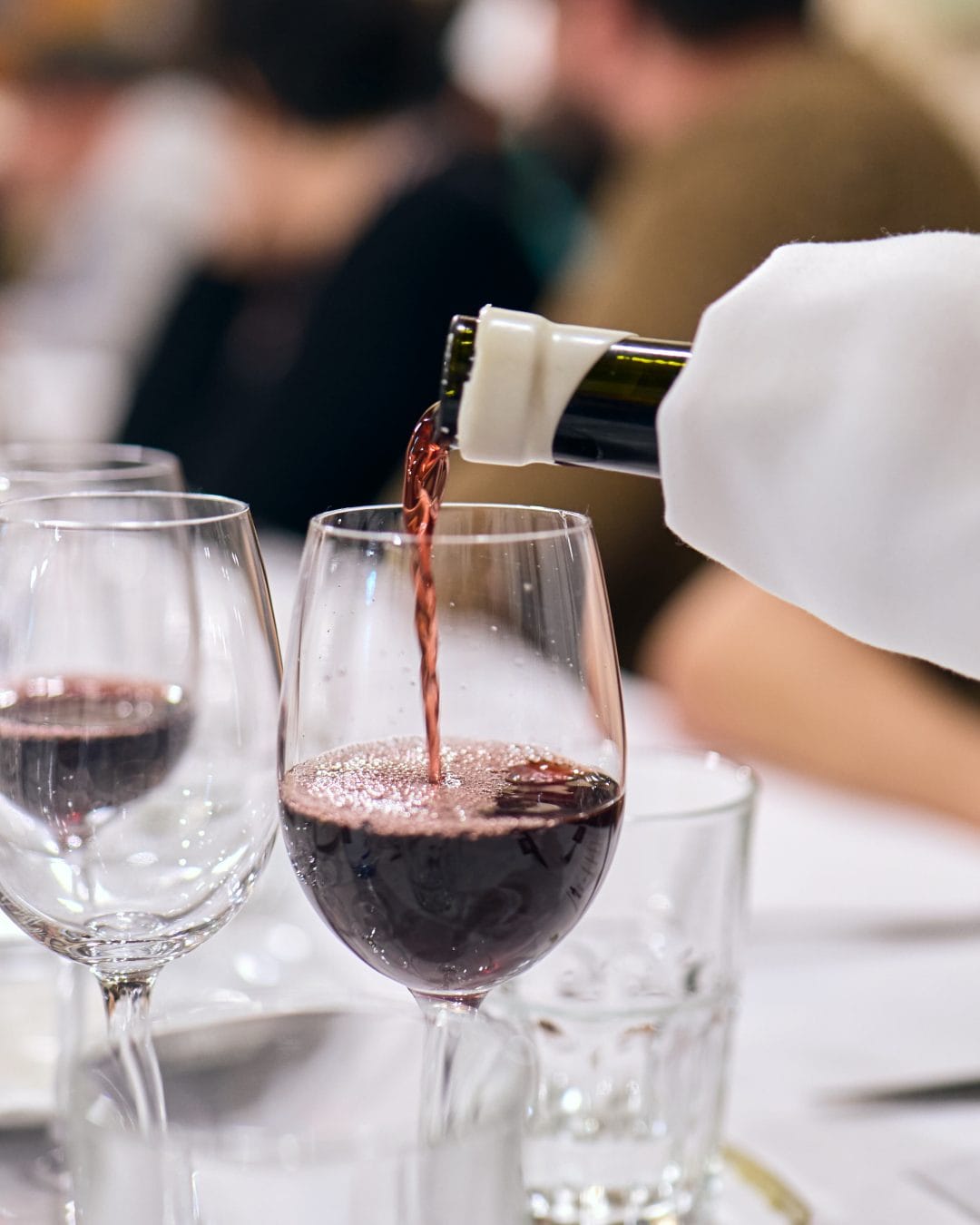 A caterer serving a glass of red wine on a private jet