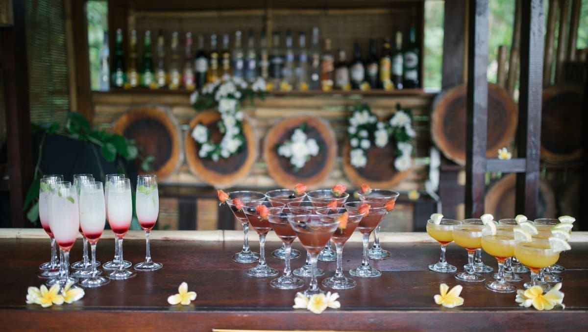 An outdoor bar with three different tropcial cocktail styles arranged on the bar top