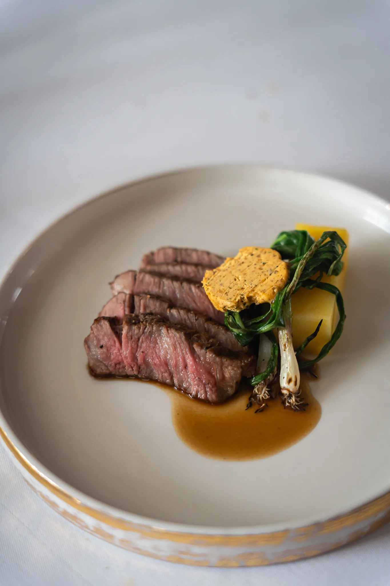 A catered dish of filet mignon steak with potato gratin and vegetables