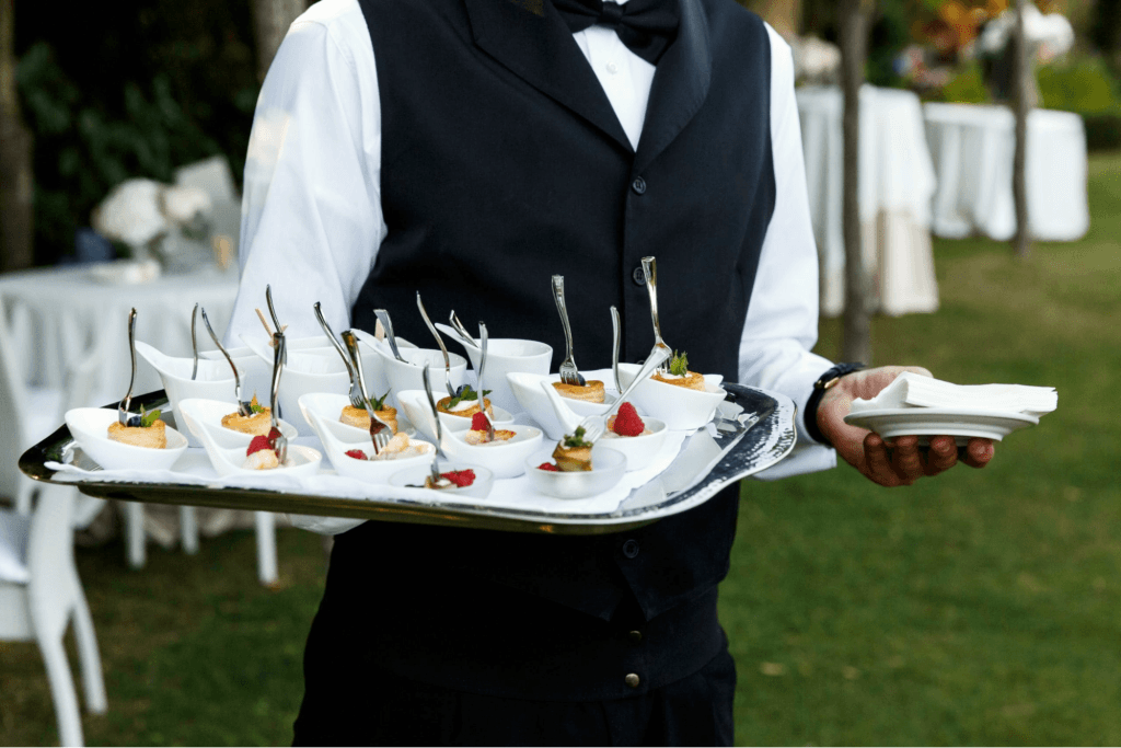 A caterer holding a plate of gourmet canapés and napkins