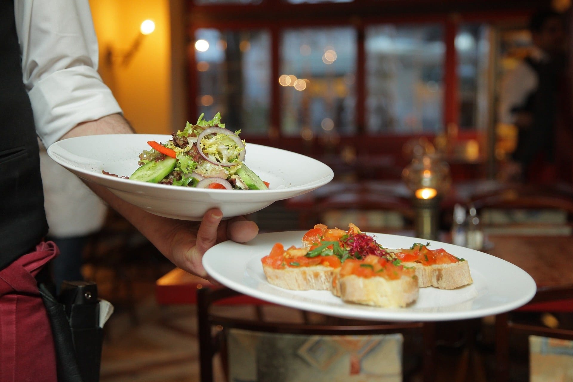 A waiter serving bruschetta and salad