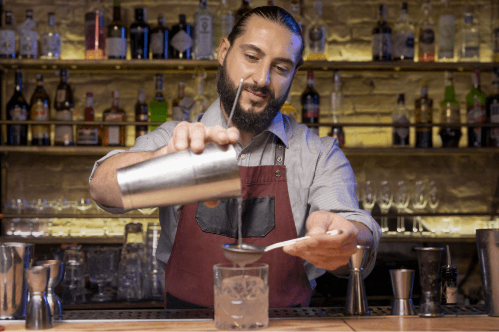 A bartender pouring a cocktail