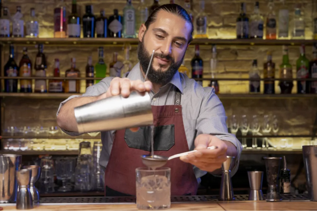 A bartender pouring a cocktail