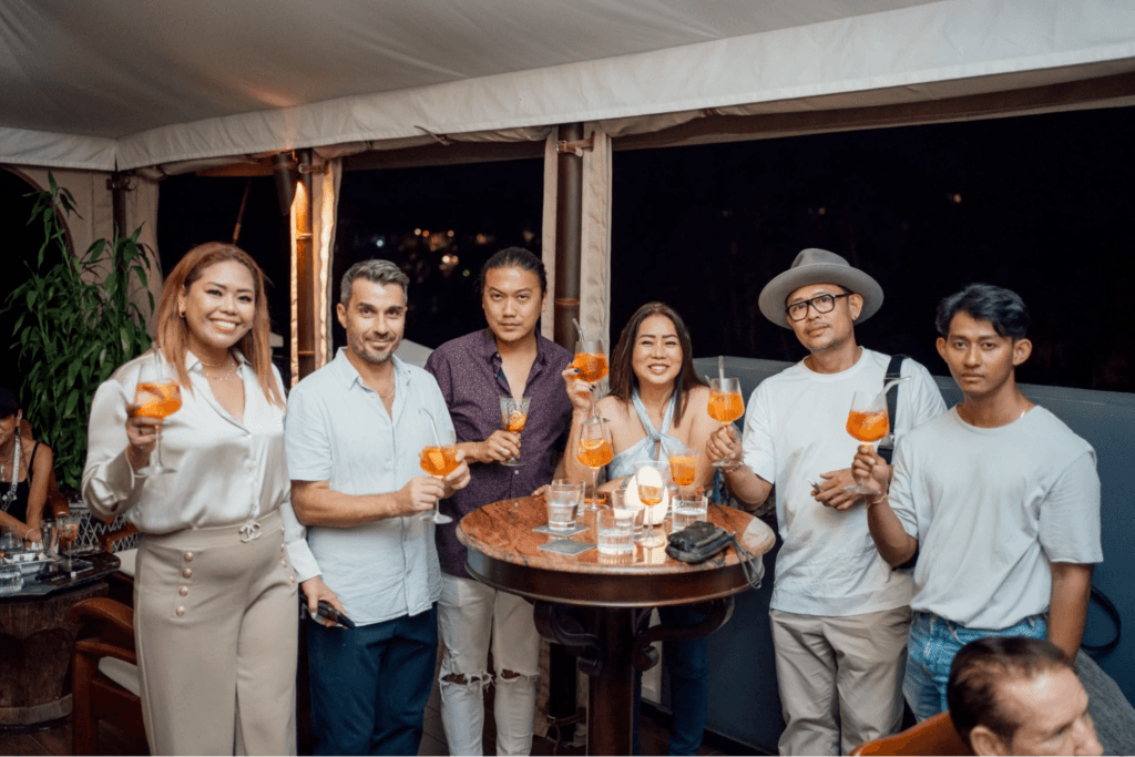 A group of people in Bali holding Aperol Spritzes