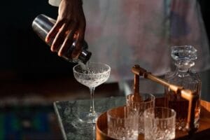 A bartender pouring a cocktail into a martini glass