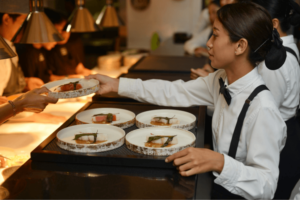 A catering staff in Bali serving dishes of plated food