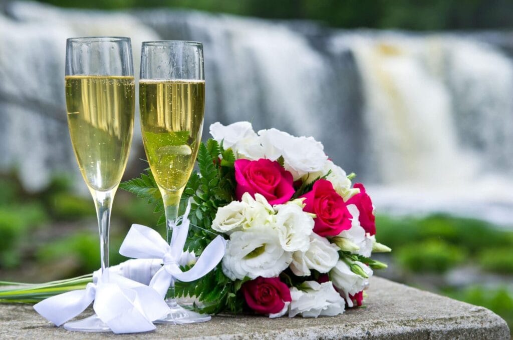 Two glasses of sparkling wine next to a wedding floral bouquet