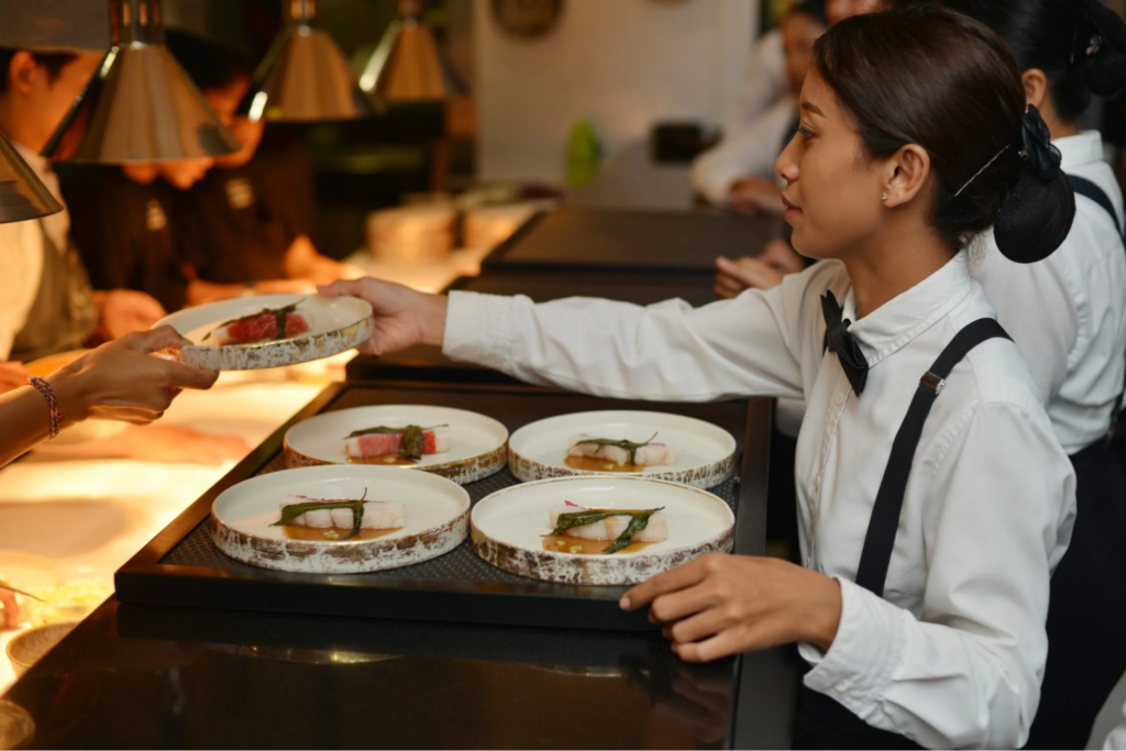 A caterer at a Bali wedding taking plates to serve guests
