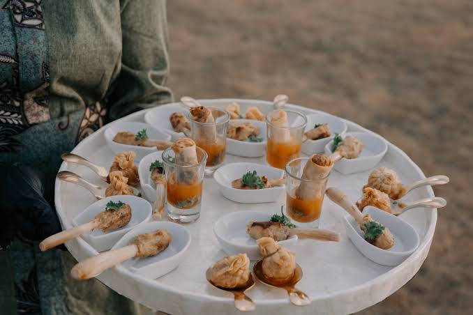 A caterer carrying a plate of Asian type small bites