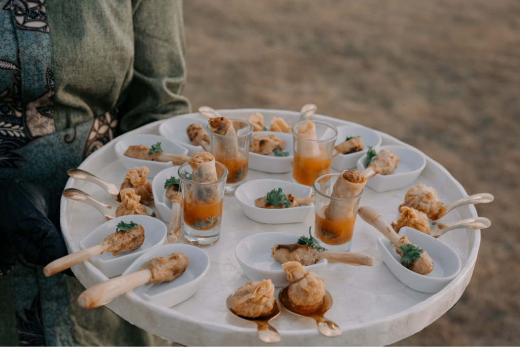 A caterer carrying a plate of different asian style small dishes